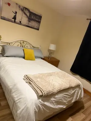 a bedroom with a white bed with a yellow blanket on it at Happy home stay in Cowlairs