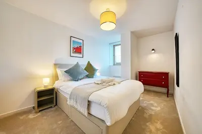 a bedroom with a bed and a red dresser at Modern Luxe Apartment in Glasgow City Centre in Glasgow