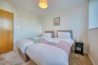 two twin beds in a room with a door at Modern Luxe Apartment in Glasgow City Centre in Glasgow
