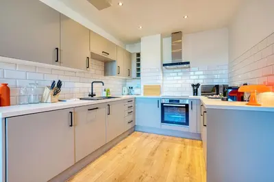 a large kitchen with white cabinets and blue appliances at Modern Luxe Apartment in Glasgow City Centre in Glasgow