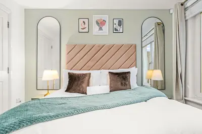 a bedroom with a large bed and two mirrors at Urban Elegance - Spacious 5-Bed Home in Glasgow in Glasgow