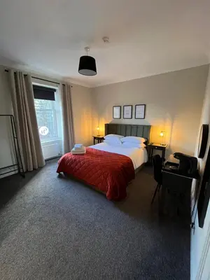 a bedroom with a large bed with a red blanket at The Graeme Hotel in Falkirk