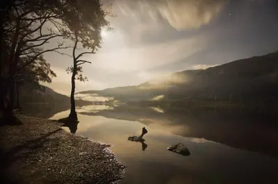 a person sitting on a rock next to a lake at Glenbruar House in Crianlarich