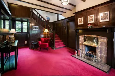 a living room with a fireplace and a red carpet at Glenbruar House in Crianlarich