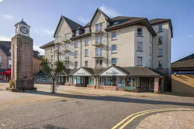 a large building with a clock tower on a street at Bay View Apartment in Oban
