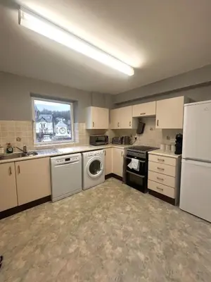 a kitchen with white cabinets and a washer and dryer at Bay View Apartment in Oban