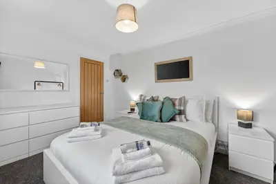 a white bedroom with a bed with towels on it at The Hide - Suburban Terraced Home in Horse Isle