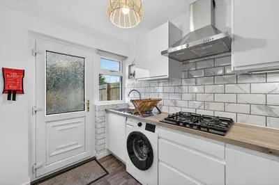 a kitchen with a washer and dryer next to a door at The Hide - Suburban Terraced Home in Horse Isle