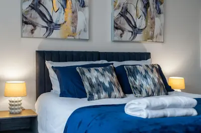 a bedroom with a blue bed with two lamps at Modern 2-Bed Flat with Balcony and Free Parking - Ideal for Contractors in Moffat