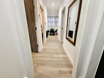 a hallway with white walls and wood floors at Bright 2-Bed Apartment in Bury Town Centre in Moffat