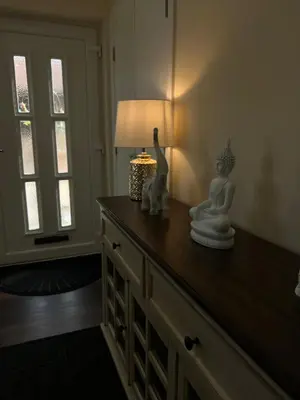 a room with a table with a lamp and statues on it at Canal View Cottage in Winchburgh