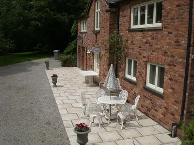 a patio with a table and chairs in front of a brick building at Garden flat at Broomfield in Moffat