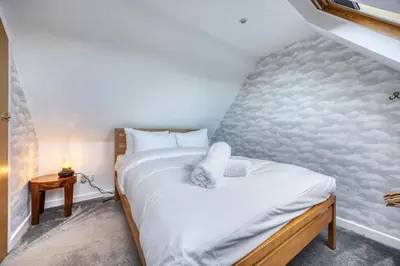 a bedroom with a bed with a white pillow on it at Cosy Lodge Getaway with Private Beach & Fireplace in Erskine