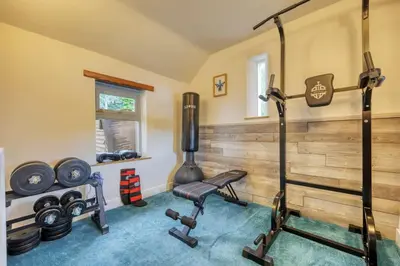 a gym with a bench and weights in a room at Cosy Lodge Getaway with Private Beach & Fireplace in Erskine