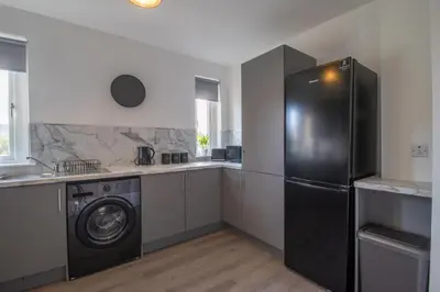 a kitchen with a refrigerator and a washing machine at The Wishy - 2 Bedroom Flat in Newmains in Newmains