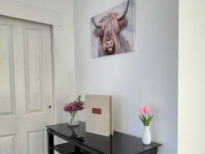 a table with a picture of a cow on the wall at Stirling apartment - free parking in Stirling