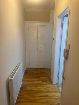 an empty hallway with a white door and wooden floors at Glasgow - Cosy 1 Bedroom Apartment in Glasgow