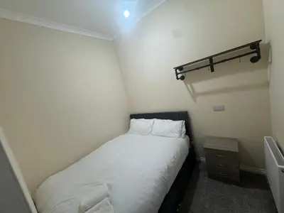 a small bedroom with a bed with white sheets and pillows at Glasgow - Cosy 1 Bedroom Apartment in Glasgow