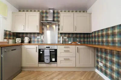 a kitchen with white cabinets and a stove top oven at Modern 3BR Home with Parking in East Kilbride