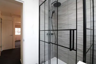 a shower in a room with a wall of glass at Modern 3BR Home with Parking in East Kilbride
