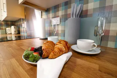 a table with a plate of pastries and a cup of coffee at Modern 3BR Home with Parking in East Kilbride