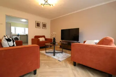 a living room with two orange chairs and a flat screen tv at Modern 3BR Home with Parking in East Kilbride