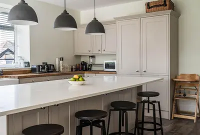 a kitchen with white cabinets and a counter with stools at Old School Mews - Shanklin - Dog Friendly in Moffat