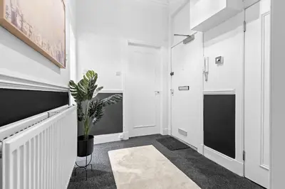 a hallway with white walls and a potted plant at Welcoming Home In Renfrew, Near Glasgow Airport - Bonnie Lodgings in Renfrew