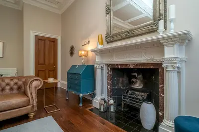 a living room with a fireplace with a mirror above it at Georgian Elegance with Patio Garden West End - Pass the Keys in Edinburgh