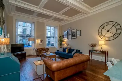 a living room with a couch and a clock on the wall at Georgian Elegance with Patio Garden West End - Pass the Keys in Edinburgh