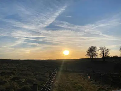 a sun setting over a field with a fence at Pentland View Campsite in Haywood