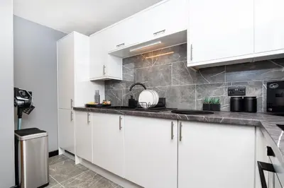 a kitchen with white cabinets and a counter top at The Apartment in Paisley