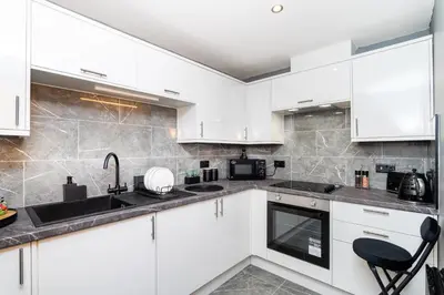 a kitchen with white cabinets and a black sink at The Apartment in Paisley