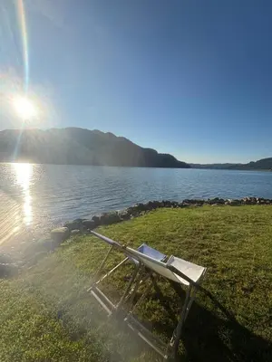 a bench sitting on the grass near a body of water at Carrick Chalets in Cairndow
