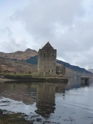an old building sitting in the middle of a body of water at Carrick Chalets in Cairndow