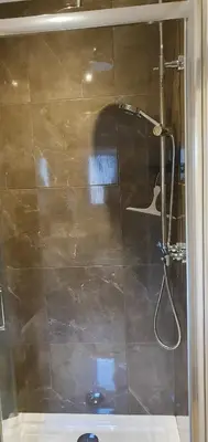 a shower with a glass door in a bathroom at Carrick Chalets in Cairndow