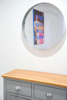 a circular mirror on top of a wooden dresser at The Lancefield Luxe in Glasgow