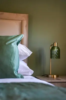 a bed with a pillow and a lamp on a table at Cruachan House in Falkirk