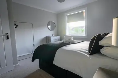 a bedroom with a large bed with a window at Cruachan House in Falkirk