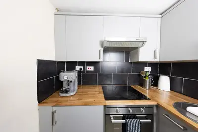 a kitchen with white cabinets and wooden counter tops at Charming and Spacious City Getaway 3 in Edinburgh