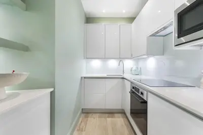 a white kitchen with white cabinets and a sink at Goldsmiths Georgian Residence in Edinburgh