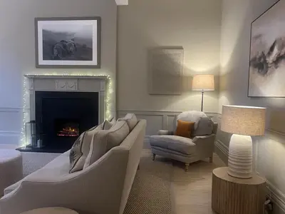 a living room with a couch and a chair and a fireplace at Goldsmiths Georgian Residence in Edinburgh