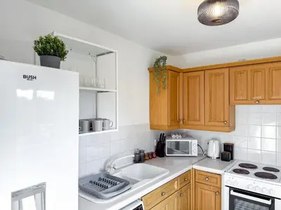 a kitchen with wooden cabinets and a sink and a microwave at Wonderfull stays new property near Glasgow 2 bedrooms in Dalmuir