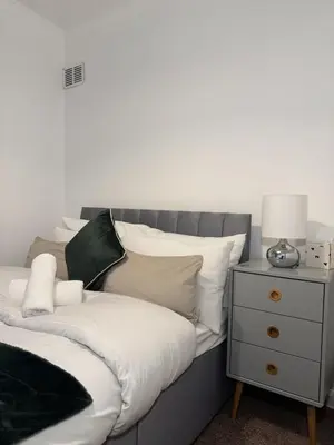 a bed with white sheets and a nightstand with a lamp at The Telford Nook in Edinburgh
