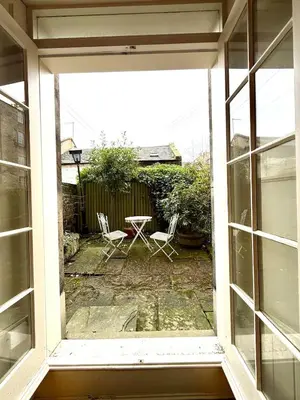an open window with a table and chairs in a yard at Cozy 1 bed Garden flat in the New Town City Centre in Edinburgh
