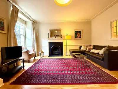 a living room with a couch and a red rug at Cozy 1 bed Garden flat in the New Town City Centre in Edinburgh