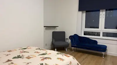 a bedroom with a bed and a chair and a window at Large double room in a house at Glasgow Westend in Knightswood