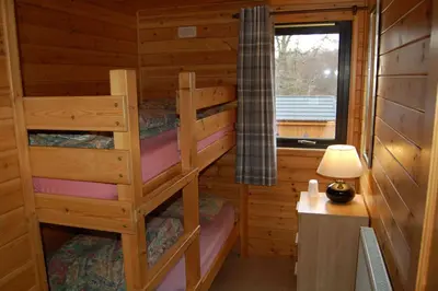 a bedroom with two bunk beds in a log cabin at Woodland Oak Log Cabin, by Meall nan Tarmachan in Killin