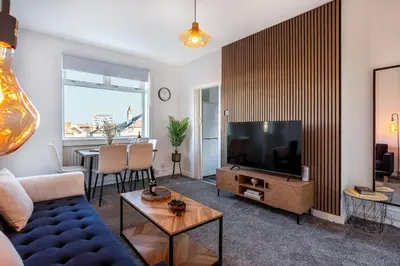 a living room with a blue couch and a television at Cosy 3 bed home in Cardonald G52 in Cardonald