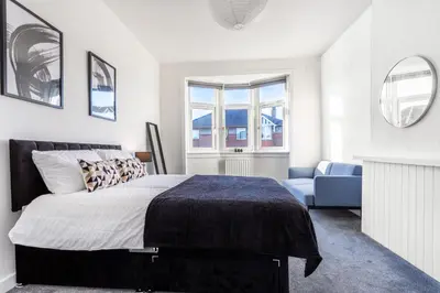 a bedroom with a bed and a blue chair at Cosy 3 bed home in Cardonald G52 in Cardonald